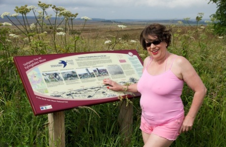 Mature BBW Speedy Bee strips naked in a field while visiting a tourist site