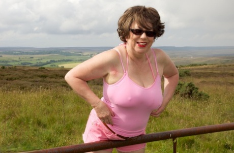 Mature BBW Speedy Bee strips naked in a field while visiting a tourist site