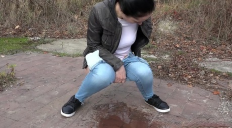 Clothed woman Corin pulls down her jeans for an urgent piss on a vacant lot