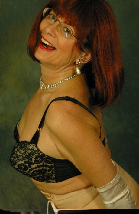 Older redhead Abigail Fraser exposes her boobs in a girdle and long gloves