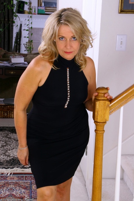 Blonde mature Leah hikes up her black dress and reveals her tasty muff