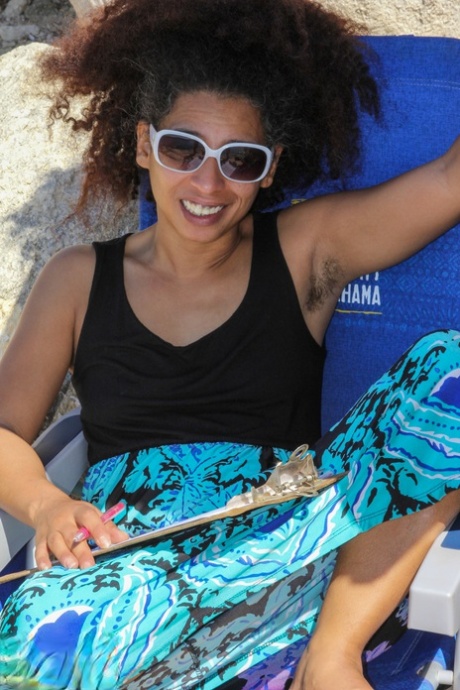 Mature ebony with hairy armpits Divine reveals her bushy cunt on the beach
