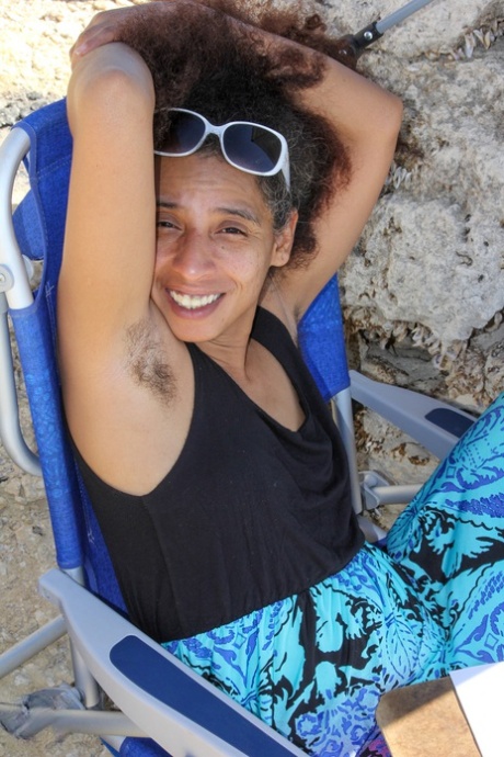 Mature ebony with hairy armpits Divine reveals her bushy cunt on the beach